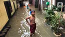 Anak-anak bermain di tengah banjir yang merendam kawasan Kebon Pala, Jakarta Timur, Selasa (25/2/2020). Akibat banjir yang tak kunjung surut, aktivitas warga di kawasan tersebut menjadi terganggu, terlebih dengan adanya pemadaman listrik. (Liputan6.com/Immanuel Antonius)