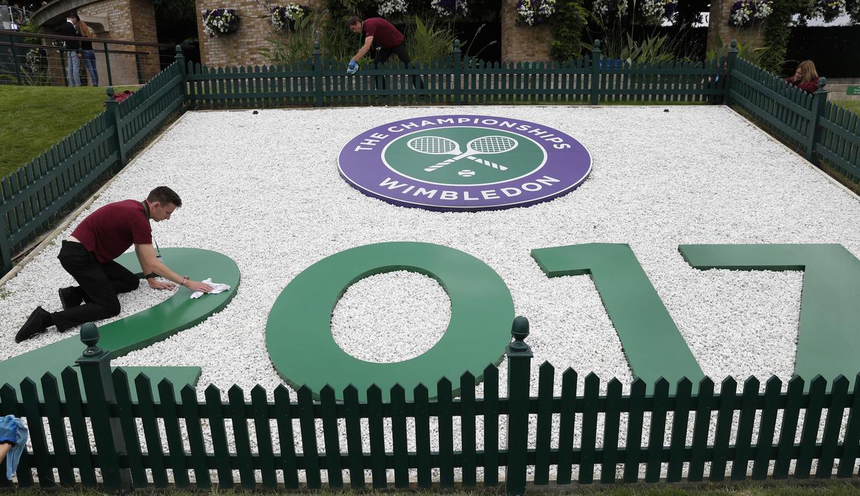 Petugas membersihkan logo Wimbledon 2017 di Wimbledon tennis club, London, (1/7/2017). Turnament Wimbledon 2017 akan berlangsung pada  3-16 Juli 2017. (AFP/Adrian Dennis)