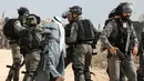 Pasukan penjaga perbatasan Israel menahan seorang pria Palestina di tengah-tengah bentrokan dengan para pengunjuk rasa yang berdemonstrasi menentang pembangunan pos terdepan Israel di dekat desa Palestina, Ramallah, Tepi Barat, Kamis (17/10/2019). (Jaafar ASHTIYEH/AFP)