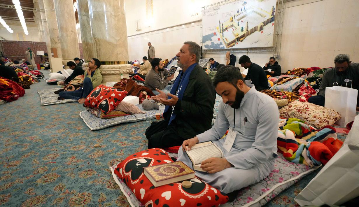 Itikaf dilakukan untuk membersihkan hati dan mendekatkan diri kepada Allah SWT. Tampak dalam foto, umat Muslim Syiah, termasuk pengunjung dari Iran dan lainnya, membaca Al-Quran, saat melaksanakan Itikaf di Masjid Kufa, selatan Baghdad, Irak, pada 12 Maret 2026. (Qassem al-KAABI/AFP)
