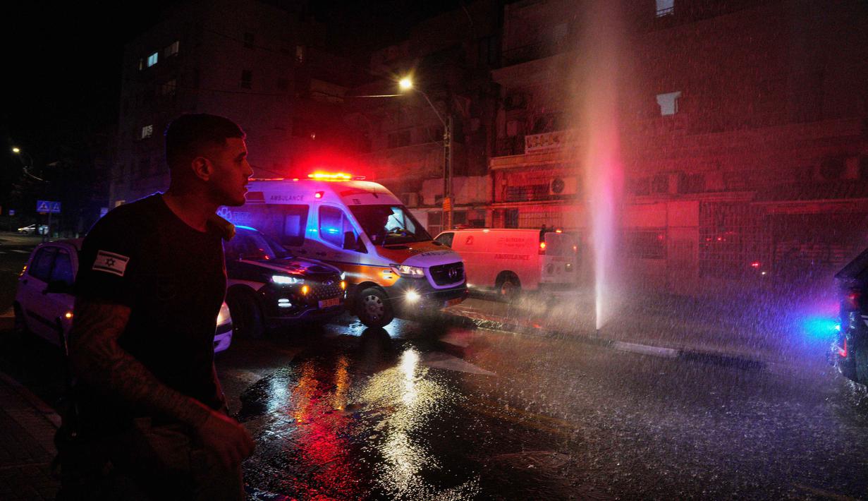 Serangan rudal Iran kali ini memicu ledakan besar yang mengguncang kota dan kebakaran pada bangunan serta kendaraan di jalanan Tel Aviv. Tampak dalam foto, air memercik dari pipa air yang rusak di lokasi sekitar serangan rudal Iran di Tel Aviv, Israel, Sabtu 28 Maret 2026 pagi waktu setempat. (AP Photo/Maya Levin)