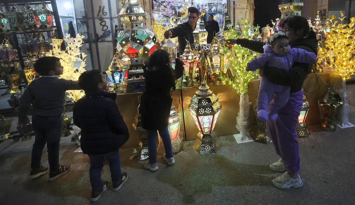 Warga Palestina berbelanja lentera tradisional "fanous" di Hebron di Tepi Barat yang diduduki pada 27 Maret 2022. Fanous merupakan lentera untuk dekorasi yang digunakan merayakan awal bulan suci Ramadan. (HAZEM BADER / AFP)