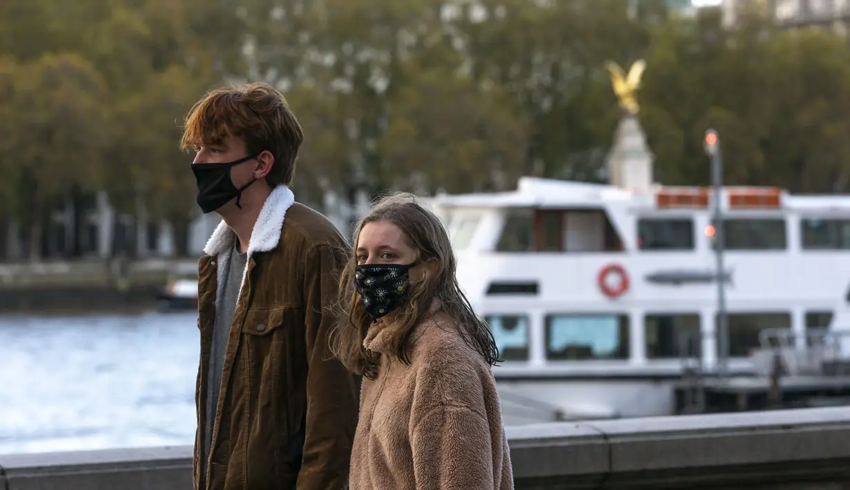 Sejumlah warga yang mengenakan masker berjalan di tepi Sungai Thames di London, Inggris (31/10/2020). Kasus baru COVID-19 di Inggris mencapai 21.915, menambah total kasus coronavirus di negara itu menjadi 1.011.660. (Xinhua/Han Yan)