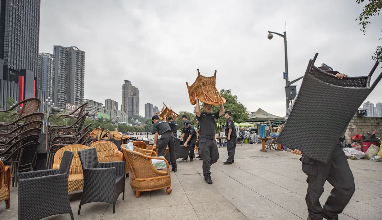 Para petugas membantu sejumlah pedagang yang tinggal di dekat tepi Sungai Yangtze memindahkan barang-barang mereka ke tempat yang lebih aman di Jalan Nanbin, Kota Chongqing, China barat daya (18/8/2020). (Xinhua/Huang Wei)
