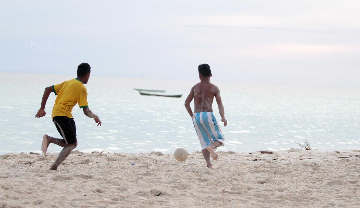 Aksi dua pemuda berebut bola saat bermain dekat pantai di Desa Matwaer, Kei Kecil, Maluku (25/12/2017). Bermain bola di pasir menjadi daya tarik tersendiri bagi anak-anak dan pemuda desa. (Bola.com/Nick Hanoatubun)