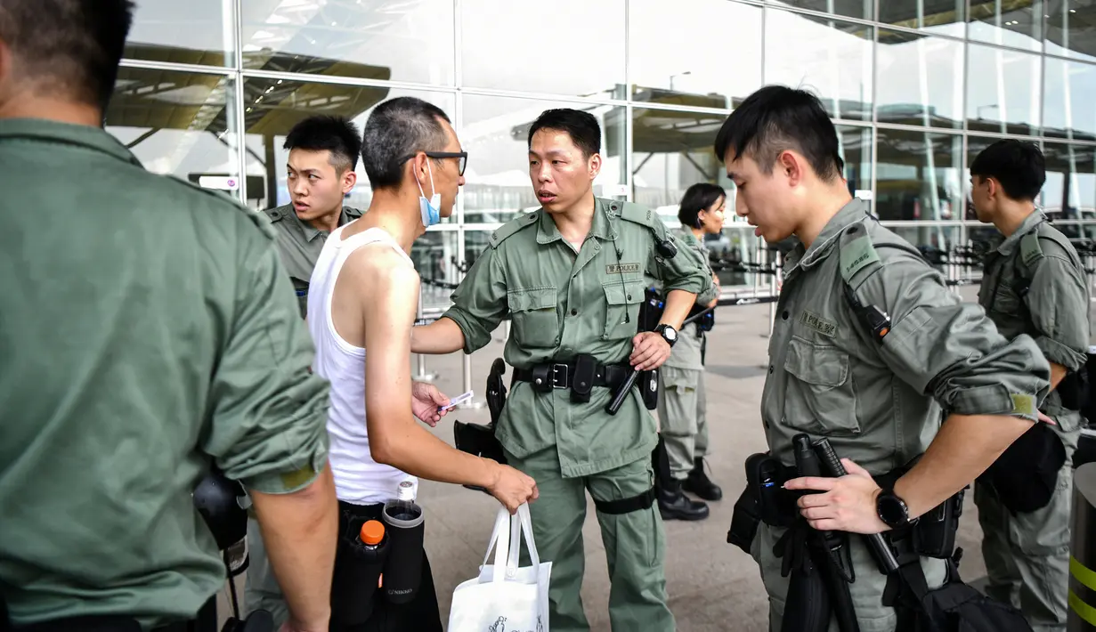 Polisi anti huru-hara memeriksa seorang pria di luar Bandara Internasional Chek Lap Kok di Hong Kong (7/9/2019). Unjuk rasa pada Sabtu, 7 September 2019, dimulai pada siang hari. (AFP Photo/Anthony Wallace)