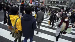 Orang-orang yang mengenakan masker berjalan di sepanjang penyeberangan pejalan kaki di daerah Shibuya, Tokyo, Selasa (5/1/2021). Ibu kota Jepang, Tokyo mengonfirmasi lebih dari 1.200 kasus virus corona COVID-19 baru pada Selasa (5/1). (AP Photo/Eugene Hoshiko)