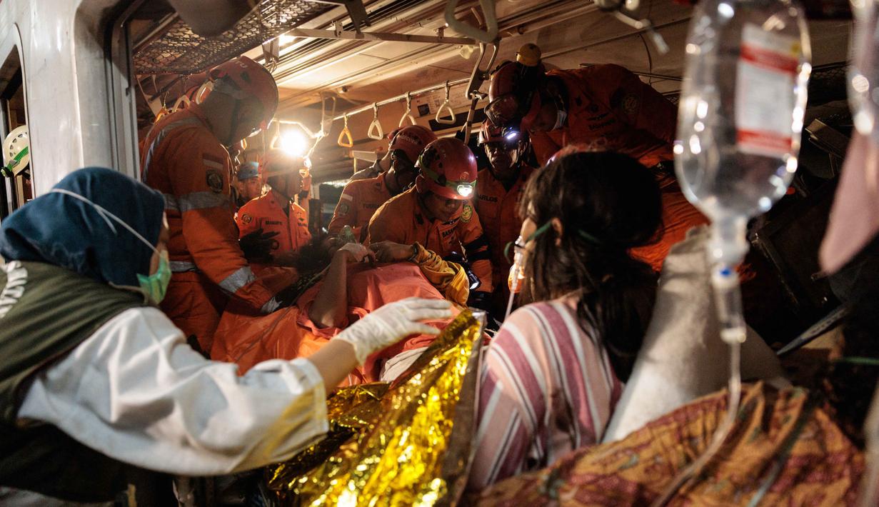 Tim pencari dan penyelamat gabungan berupaya menyelamatkan salah satu korban yang terjebak di dalam gerbong setelah lokomotif Kereta Api Jarak Jauh (KAJJ) Argo Bromo Anggrek menabrak gerbong belakang Kereta Rel Listrik (KRL) Commuter Line di stasiun Bekasi Timur, Bekasi, Jawa Barat pada Selasa 28 April 2026. (Yasuyoshi Chiba/AFP)