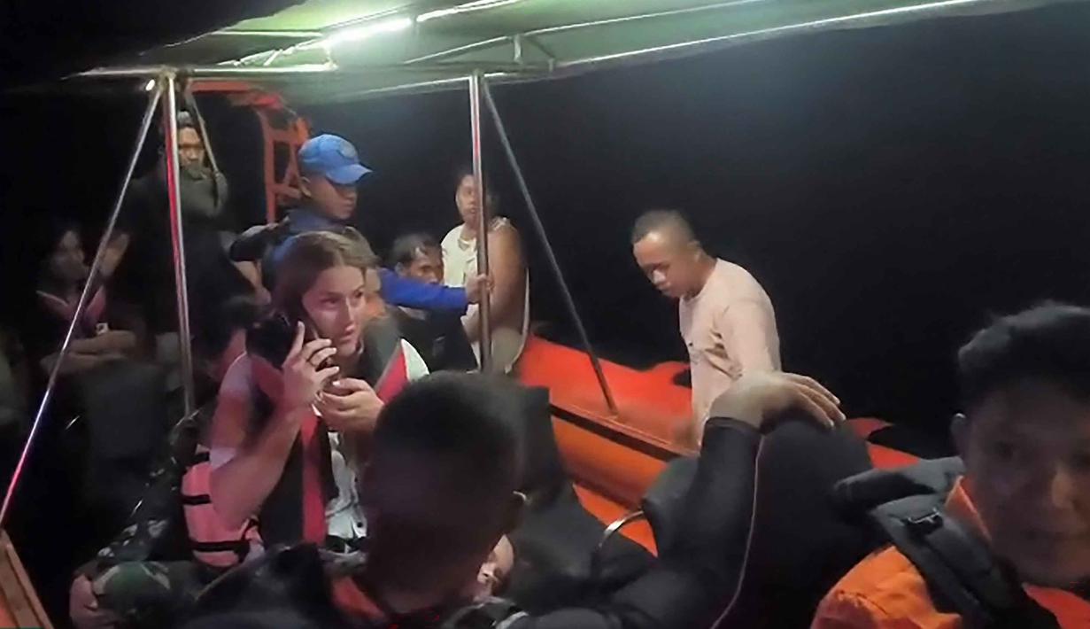 Sementara itu, empat lainnya yang merupakan wisatawan asal Spanyol yang diduga berada dalam satu rombongan keluarga masih dinyatakan hilang dan terus dicari oleh tim SAR gabungan. Tampak foto yang dirilis pada 27 Desember 2025 oleh Badan Nasional Pencarian dan Penyelamatan Indonesia (BASARNAS Labuan Bajo) ini menunjukkan anggota tim pencarian dan penyelamatan mengevakuasi wisatawan asing di perairan Pulau Padar, Labuan Bajo, Nusa Tenggara Timur, setelah sebuah kapal wisata mengalami kerusakan mesin dan tenggelam. (Handout/BASARNAS/AFP)