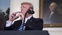 Presiden Amerika Serikat (AS), Donald Trump meminum air dari botol mineral disela menyampaikan pidatonya di Ruang Diplomatik, Gedung Putih, Rabu (15/11). Video Trump minum tersebut menuai komentar dari warganet di media sosial. (NICHOLAS KAMM/AFP)