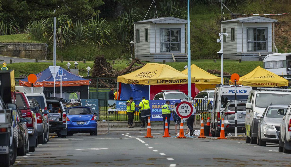 Sebagai informasi, longsor terjadi pada Kamis (22/1/2026) sekitar pukul 09.30 waktu setempat, ketika material tanah dan bebatuan meluncur deras menimpa area perkemahan. Tampak dalam foto, petugas darurat menutup jalan setelah tanah longsor sementara pencarian sedang dilakukan oleh layanan darurat setempat untuk orang hilang di Gunung Maunganui, Tauranga, Selandia Baru pada Kamis 22 Januari 2026. (DJ MILLS/AFP)