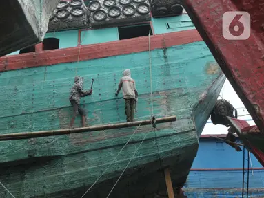 Pekerja menyelesaikan perbaikan kapal nelayan di Galangan Kapal Muara Angke, Jakarta Utara, Kamis (23/5/2024). (merdeka.com/Imam Buhori)