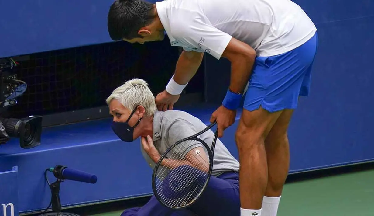 Petenis Serbia, Novak Djokovic, menghampiri hakim garis yang terkena bola pada AS Terbuka di Flushing Meadows, Senin (7/9/2020). Djokovic didiskualifikasi karena memukulkan bola tenis ke arah hakim garis. (AP/Seth Wenig)