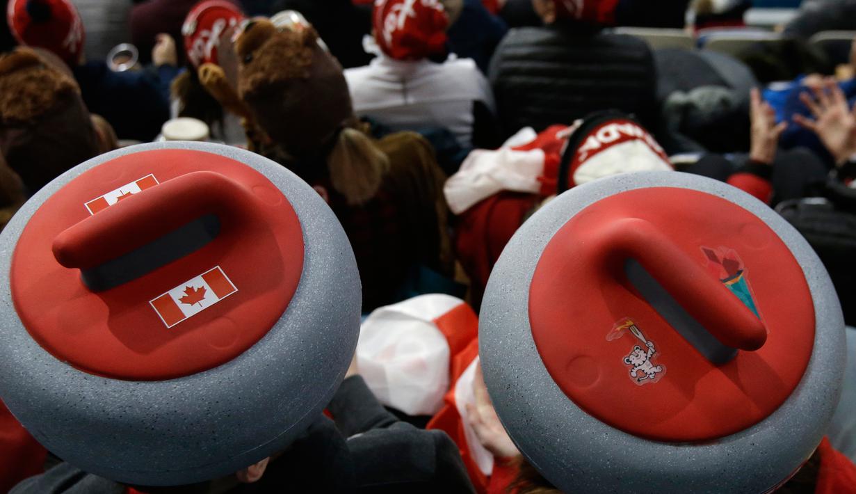 Penonton mengenakan atribut kepala unik saat menyaksikan cabang curling ganda campuran antara Kanada dan Swiss pada Olimpiade Musim Dingin 2018 di Gangneung, Korsel, Selasa (13/2). Olimpiade ini berlangsung hingga 25 Februari mendatang. (AP/Aaron Favila)