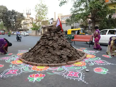 Warga menghiasi jalan di sekitar "Holika", Ahmedabad, India, Minggu (12/3). Bahan bakar Holika adalah kue yang terbuat dari kotoran sapi dan kelapa. (AFP PHOTO / SAM PANTHAKY)