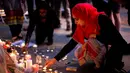 Seorang wanita menyalakan lilin sehari setelah serangan bunuh diri di sebuah konser Ariana Grande di Albert Square, Manchester, Inggris, (23/5). (AP Photo/Emilio Morenatti)