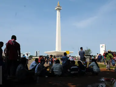 Sejumlah pengunjung beristirahat di bawah pohon yang ada di sekitar areal Monumen Nasional, Jakarta, Jumat (1/1/2016). Hari libur tahun baru 2016 dimanfaatkan ribuan warga untuk berwisata di kawasan Monumen Nasional. (Liputan6.com/Helmi Fithriansyah)