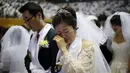 Seorang wanita terharu saat mengikuti pernikahan massal di Gereja Unifikasi Korea Selatan, (20/02). Pernikahan massal di gereja ini telah dimulai pada awal 1960-an yang baru diikuti oleh puluhan pasangan. (REUTERS / Kim Hong - Ji)