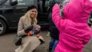 Aktris asal Kanada, Pamela Anderson memberikan buah-buahan kepada seorang anak di pengungsian Grande-Synthe, Prancis (25/1). Dalam kunjungannya, Pamela menyumbangkan buku anak-anak, makanan serta perlengkapan lainnya. (AFP/Philippe Huguen)
