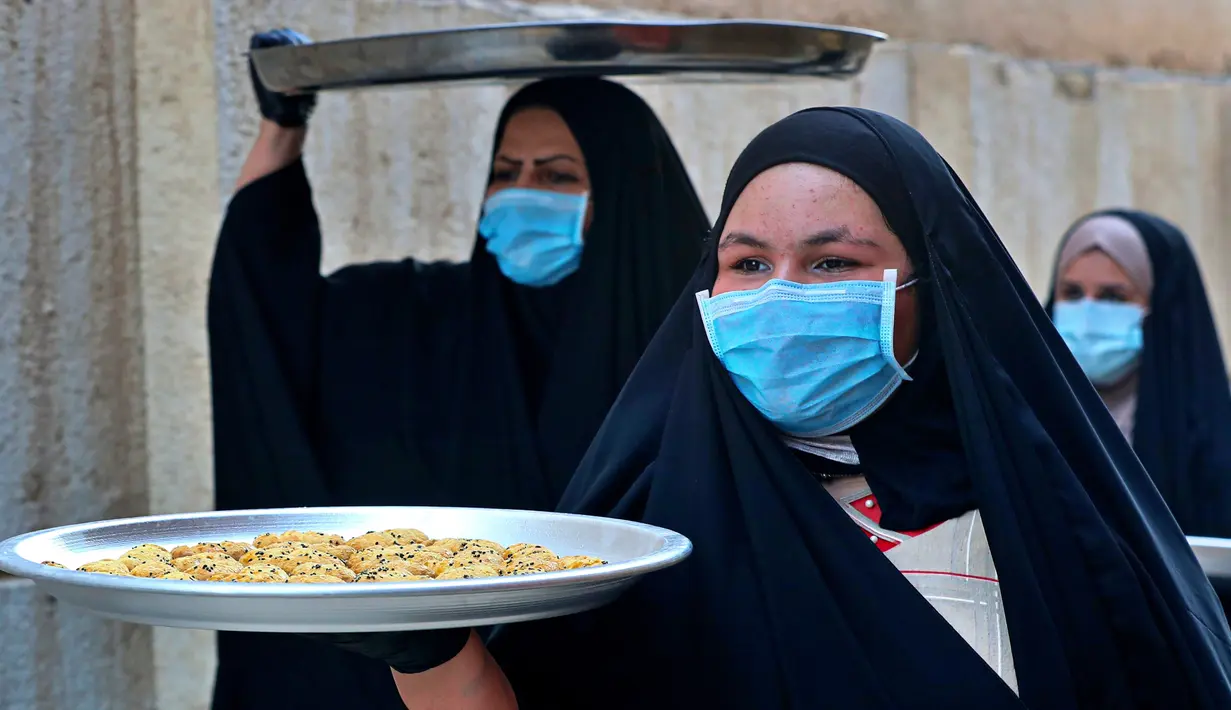 Sejumlah perempuan mengenakan masker untuk melindungi diri dari paparan virus corona COVID-19 saat membawa kue untuk perayaan Idul Fitri yang akan datang di Basra, Irak, Jumat (22/5/2020). Idul Fitri menandai berakhirnya bulan suci Ramadan. (AP Photo/Nabil al-Jurani)