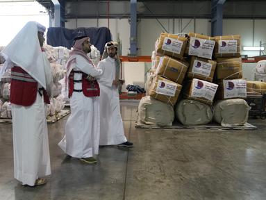 Karyawan Bulan Sabit Merah Qatar melewati pasokan paket bantuan yang akan dikirim untuk wilayah yang dilanda gempa di Turki, di Pangkalan Udara Al-Udeid di Qatar, Selasa, 7 Februari 2023. Gempa bumi dahsyat melanda Turki tenggara dan Suriah Senin dini hari, merobohkan ratusan bangunan serta menewaskan dan melukai ribuan orang. (AP Photo/Kamran Jebreili)