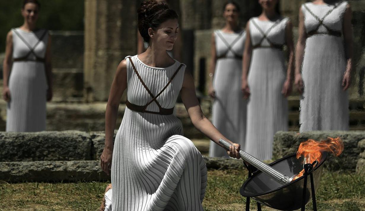 Aktris Yunani, Katerina Lechou, menyalakan api olimpiade dalam suatu upacara di Candi Hera yang terletak di bekas kota tua Olympia, Yunani, Kamis (21/4/2016). Olympia adalah kota dimana olimpiade lahir tahun 776 Sebelum Masehi. (AFP/Aris Messinis)