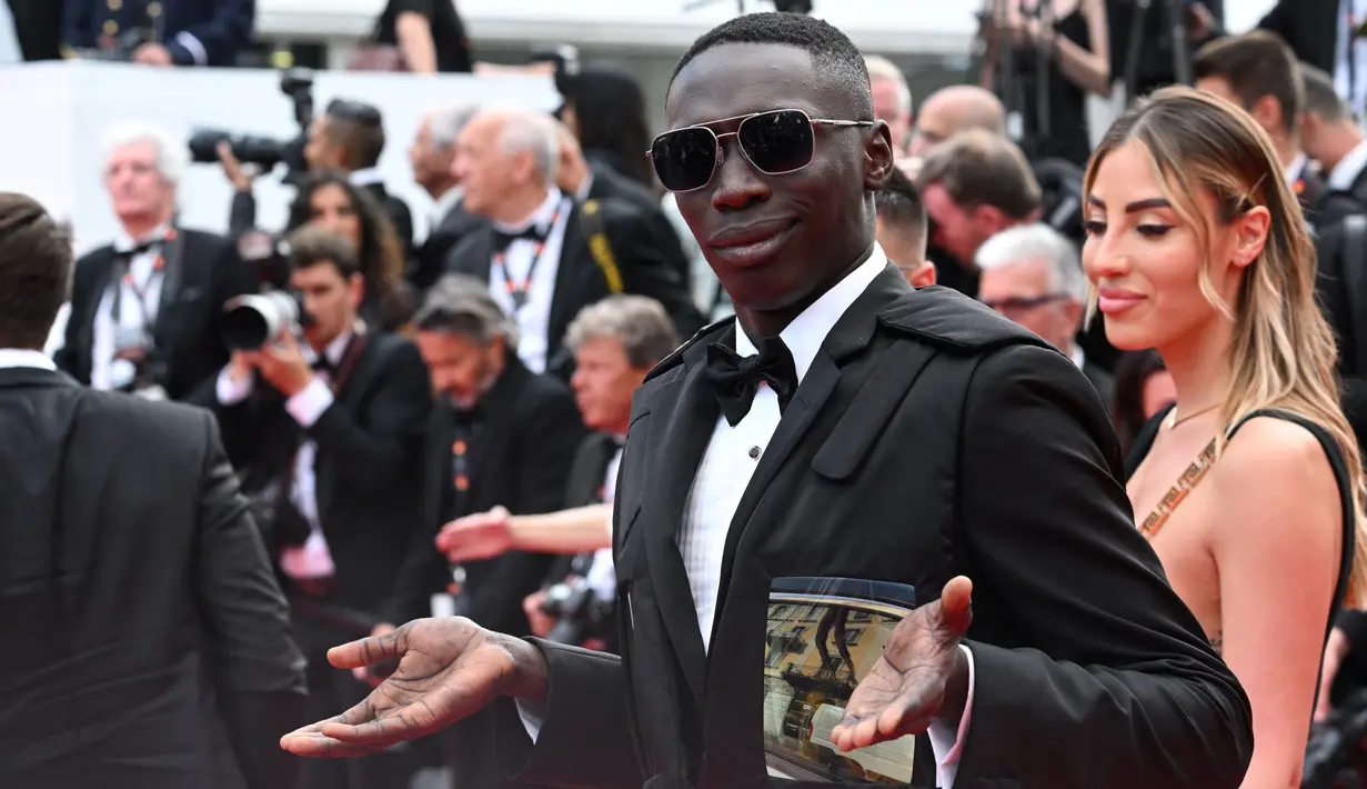 <p>Influencer Italia Khaby Lame tiba untuk pemutaran film "Top Gun : Maverick" selama Festival Film Cannes edisi ke-75 di Cannes, Prancis selatan (18/5/2022). Khaby tampil dengan setelan jas dan kaca mata hitam. (AFP/Christophe Simon)</p>