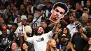 Seorang penonton membawa poster berbentuk muka pebasket San Antonio Spurs, Victor Wembanyama pada laga NBA musim 2023/2024 melawan Dallas Mavericks di AT&T Center in San Antonio, Texas, Kamis (27/10/2023). (AFP/Chandan Khanna)