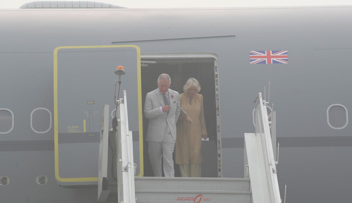 Pangeran Charles dan istrinya, Camilla bersiap turun dari sebuah pesawat yang terselimuti kabut asap setibanya di New Delhi, India, Rabu (8/11). Pasangan dari Kerajaan Inggris itu akan berada di negara Anak Benua selama dua hari. (AP Photo/Manish Swarup)