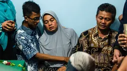 Orangtua dari korban jatuhnya pesawat Lion Air JT 610 Jannatun Cintya Dewi duduk depat peti jenazah anaknya sebelum pemakaman di kediaman kawasan Sukodono, Sidoarjo, Jawa Timur, Kamis (1/11). (JUNI KRISWANTO / AFP)