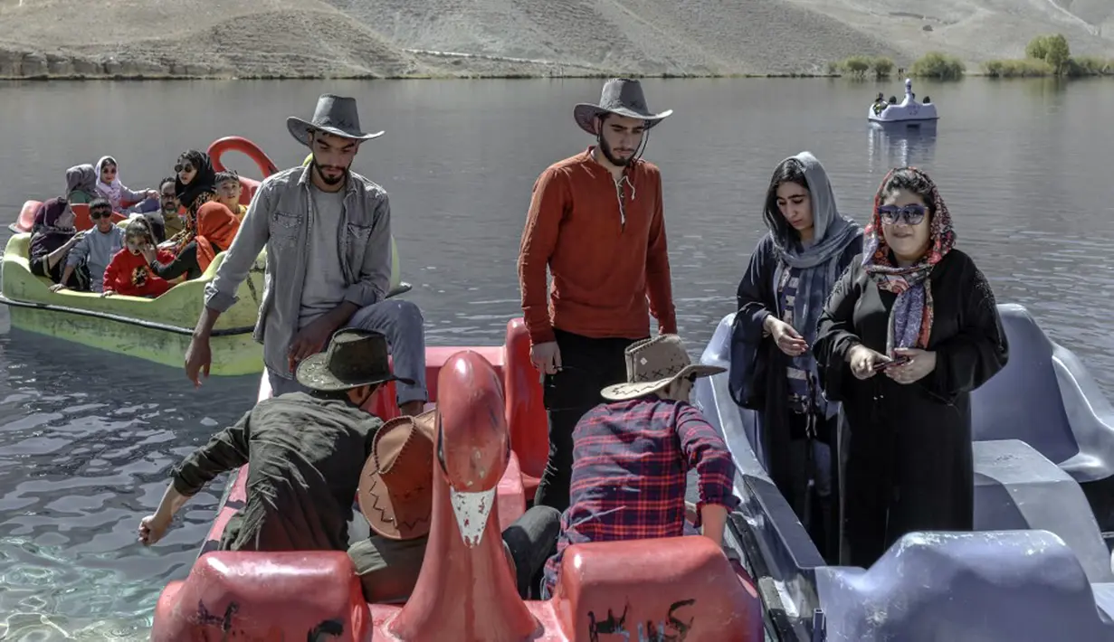 Wisatawan duduk di atas perahu dayung untuk berkendara di Danau Band e-Amir, Provinsi Bamiyan, 4 Oktober 2021. Danau Band-e Amir yang memiliki perairan biru menakjubkan disebut juga sebagai Grand Canyon Afghanistan. (BULENT KILIC/AFP)