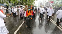 Seorang petugas kebersihan DKI Jakarta membawa kantung plastik untuk membersihkan sampah  usai aksi damai 2 Desember di kawasan Jalan MH Thamrin, Jakarta, Jumat (2/12). (Liputan6.com/Ferbian Pradolo)