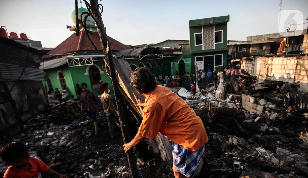Warga memilah barang yang masih bisa diselamatkan di reruntuhan rumah akibat kebakaran yang melanda pemukiman di jalan Bojong Kavling RT 16/RW04 Kelurahan Rawa Buaya, Jakarta, Rabu (5/1/2022). Kebakaran terjadi Selasa (4/1/2022) menghanguskan setidaknya 14 rumah warga. (Liputan6.com/Johan Tallo)