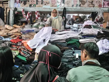 Pedagang melayani pembeli seragam sekolah di Pasar Mester Jatinegara, Jakarta Timur, Senin (3/1/2022). Salah satu pedagang mengungkapkan penjualan seragam sekolah mengalami peningkatan 50 persen seiring pemberlakuan PTM di Jakarta yang kembali digelar 100 persen. (merdeka.com/Iqbal S. Nugroho)