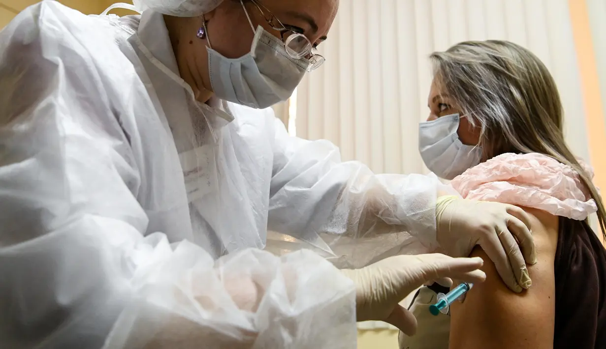 Perawat menyuntikkan vaksin corona Sputnik V di tengah pandemi yang sedang berlangsung di sebuah klinik di Moskow, Sabtu (5/12/2020). Presiden Rusia Vladimir Putin memerintahkan pihak berwenang memulai vaksinasi massal untuk orang-orang berisiko tinggi tertular Covid-19. (Kirill KUDRYAVTSEV/AFP)