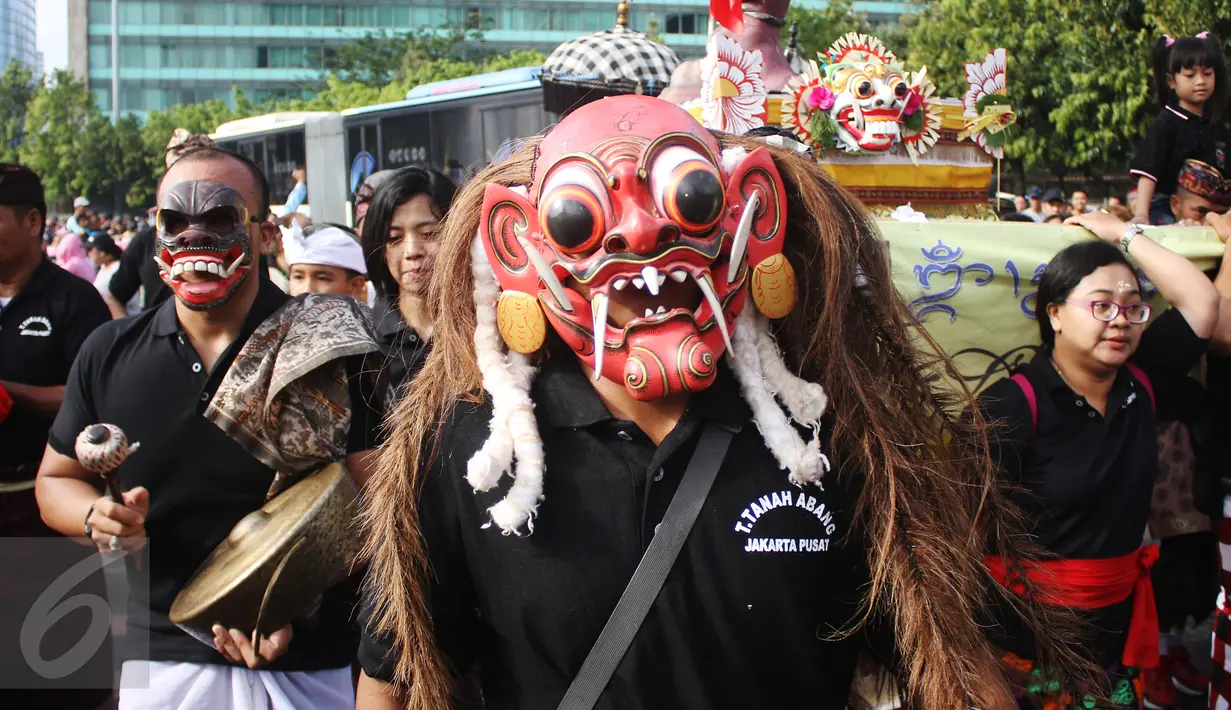Seorang pria mengenakan topeng saat sosialisasi pawai ogoh-ogoh di kawasan CFD, Bundaran HI, Jakarta, Minggu (19/3). Pawai ogoh-ogoh akan diadakan secara besar di Pura Agung Wira Satya Bhuana, Jakarta, pada Senin (27/3). (Liputan6.com/Angga Yuniar)