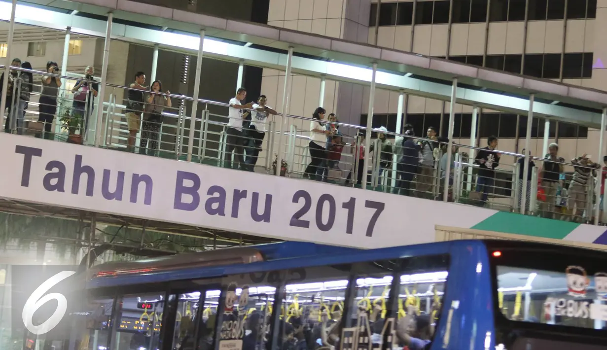 Sejumlah warga berdiri di jembatan penyebrangan Bundaran HI di Jakarta, Sabtu (31/12). Jelang pergantian tahun, kawasan tersebut mulai dipadati warga dari berbagai daerah, meskipun tidak diberlakukan car free night. (Liputan6.com/Immanuel Antonius)