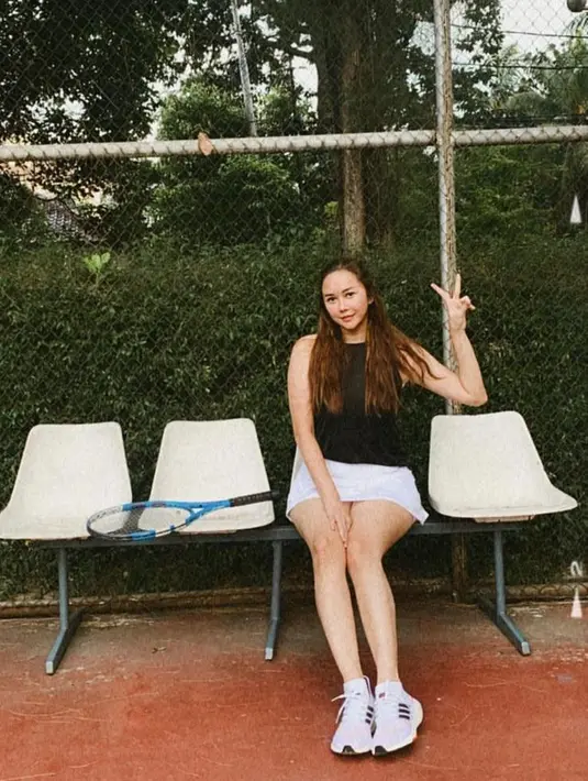 Selain golf, Aura Kasih juga menyukai tennis. Dalam potret itu, ia tampil manis mengenakan tank top hitam, mini skirt putih, dan sneakers warna senada dengan bawahannya. (Instagram/aurakasih).