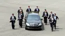 Para pengawal berlari di samping mobil yang membawa Pemimpin Korea Utara Kim Jong-un saat akan makan siang dalam KTT Korea Selatan-Korea Utara di zona demiliterisasi, Panmunjom, Korea Selatan, Jumat (27/4). (Korea Summit Press Pool/AFP)