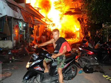 Seorang warga menyelamatkan diri dari kebakaran yang terjadi di belakang Senayan City, Jakarta, Minggu (3/7) dini hari. Sejumlah rumah semi permanen terbakar 38 mobil pemadam kebakaran dikerahkan. (Liputan6.com/Helmi Afandi)