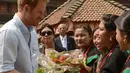 Pangeran Harry menerima buket bunga dari Panchakanya atau lima perawan khas budaya tradisional Nepal saat mengunjungi salah satu situs warisan dunia, Patan Durbar Square di Kathmandu, Minggu (20/3). (REUTERS/Prakash Mathema/Pool)