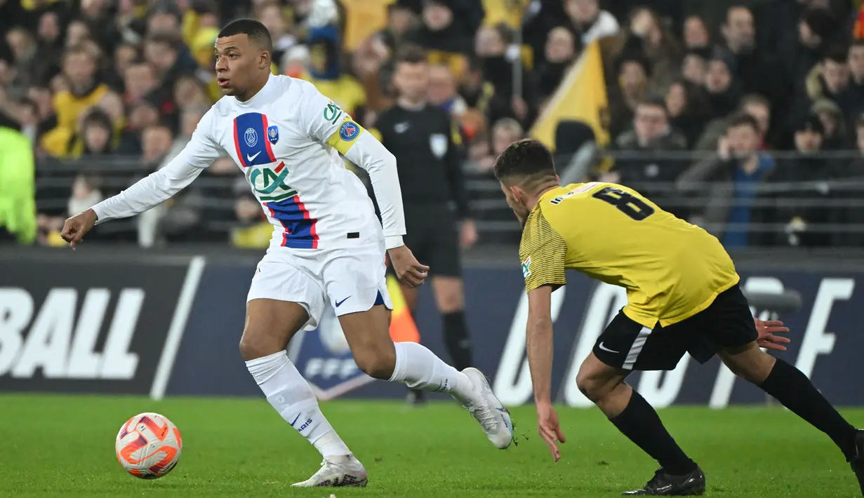Pemain PSG, Kylian Mbappe (kiri) berusaha melewati pemain US Pays de Cassel, Clement Boudjema pada laga babak 32 besar Coupe de France 2022/2023 di Stade Bollaert-Delelis, Selasa (24/1/2023) dini hari WIB. Mbappe berhasil mencetak lima dari tujuh gol kemenangan Paris Saint-Germain. (AFP/Francois Lo Presti)