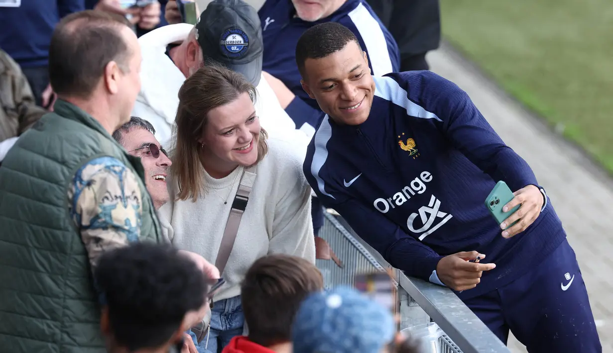 Penyerang timnas Prancis, Kylian Mbappe berswafoto dengan para penggemar di akhir sesi latihan di Stadion Home Deluxe Arena di Paderborn, Jerman, pada 13 Juni 2024. (FRANCK FIFE/AFP)
