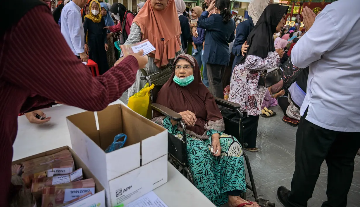 Sebanyak 32 ribu mustahik atau warga yang berhak menerima manfaat zakat mendapatkan bantuan. Tampak dalam foto, seorang wanita lanjut usia menerima bantuan uang tunai di masjid Cheng Hoo, Surabaya, Jawa Timur pada Rabu 4 Maret 2026. (JUNI KRISWANTO/AFP)