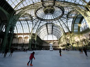 Orang-orang  berseluncur di arena ice skating di bawah kubah kaca mewah legendaris, Grand Palais, Paris, Senin (17/12). Arena ice skating musiman ini terbuka untuk umum selama liburan Natal. (AP Photo/Christophe Ena)