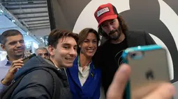 Aktor Keanu Reeves (kanan) berselfie dengan para pengunjung di Stand Motor Arch selama pameran Moto Milano 2017 (EICMA l'Esposizione Internationale del Ciclo e Motociclo) di Milan, Italia, (8/11). (AFP Photo/Miguel Medina)