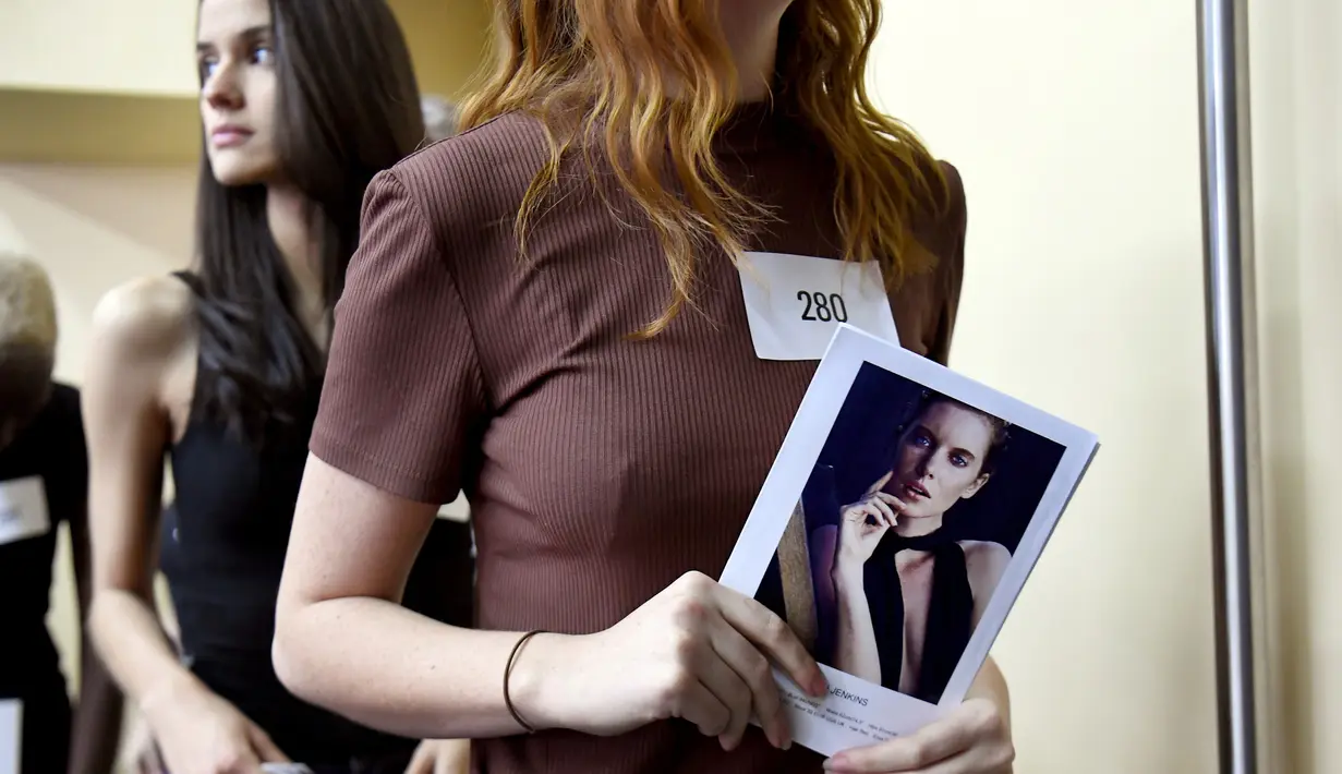 model memegang foto dirinya ketika menunggu casting untuk Melbourne Fashion Week, Australia (24/7/2019). Lebih dari 400 model tampil di Melbourne Meat Market yang ikonik menjadi salah satu dari 120-150 model yang dipilih untuk mode tersebut. (AFP Photo/William West)