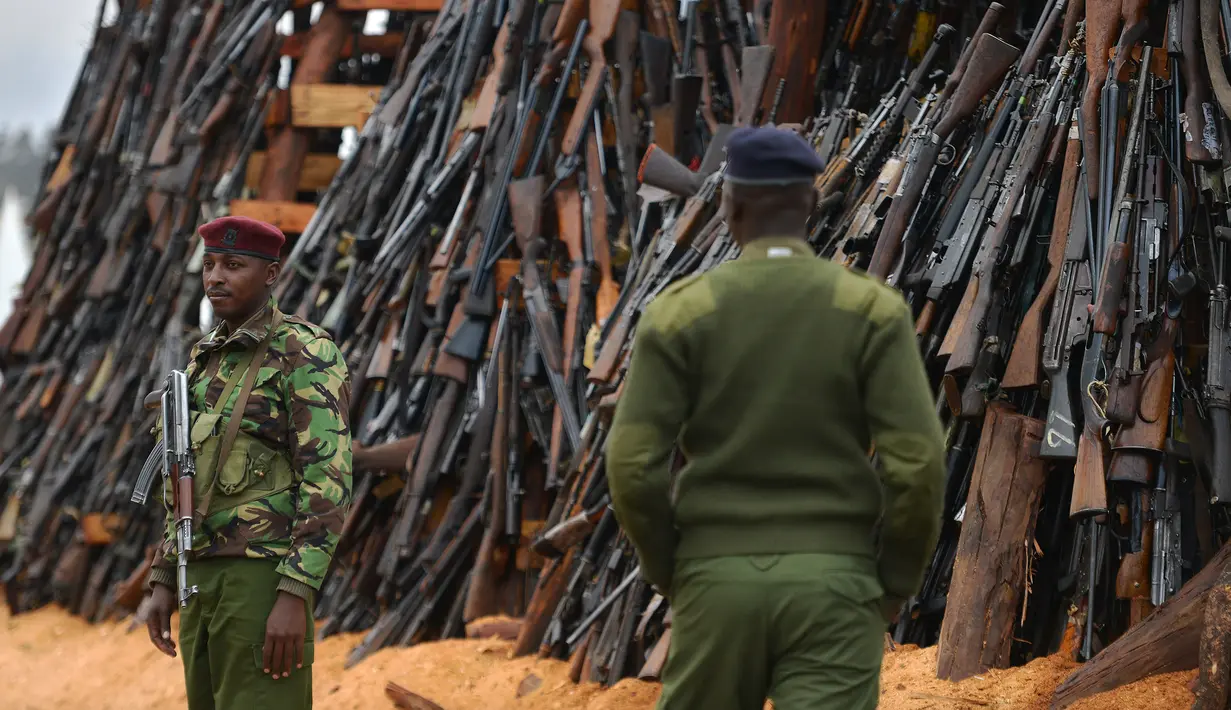 Petugas keamanan berjaga di depan senjata ilegal yang akan dibakar di Kajiado County, Kenya (15/11). Selain itu juga, tingkat perampokan yang menggunakan senjata makin tinggi dan mengganggu keamanan Kenya. (AFP/Tony Karumba)