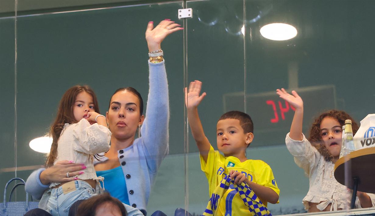Georgina Rodriguez dan buah hati dari pasangan pemain Al Nassr Cristiano Ronaldo saat menghadiri pertandingan antara Al Nassr melawan Al Riyadh dalam laga pekan ke-16 Saudi Pro League 2023/2024 yang digelar di Al Awwal Park, Sabtu (9/12/2023) dini hari WIB. (AFP/Fayez Nureldine)