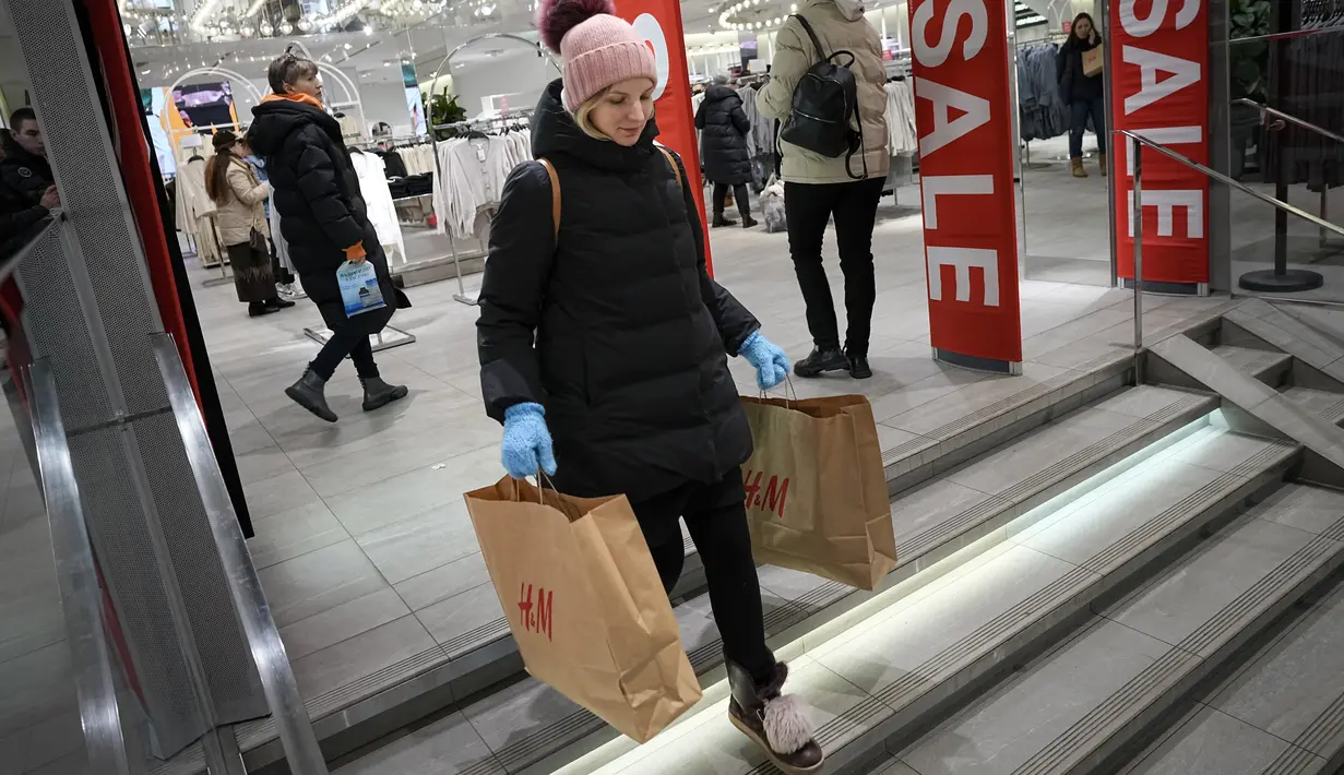 Seorang perempuan membawa dua kantong belanja meninggalkan toko H&M pada hari terakhir pembukaan di Moskow, Rusia, Rabu (30/11/2022). H&M menutup seluruh tokonya sebagai bentuk protes atas serangan Rusia ke Ukraina.  (AP Photo/Alexander Zemlianichenko)